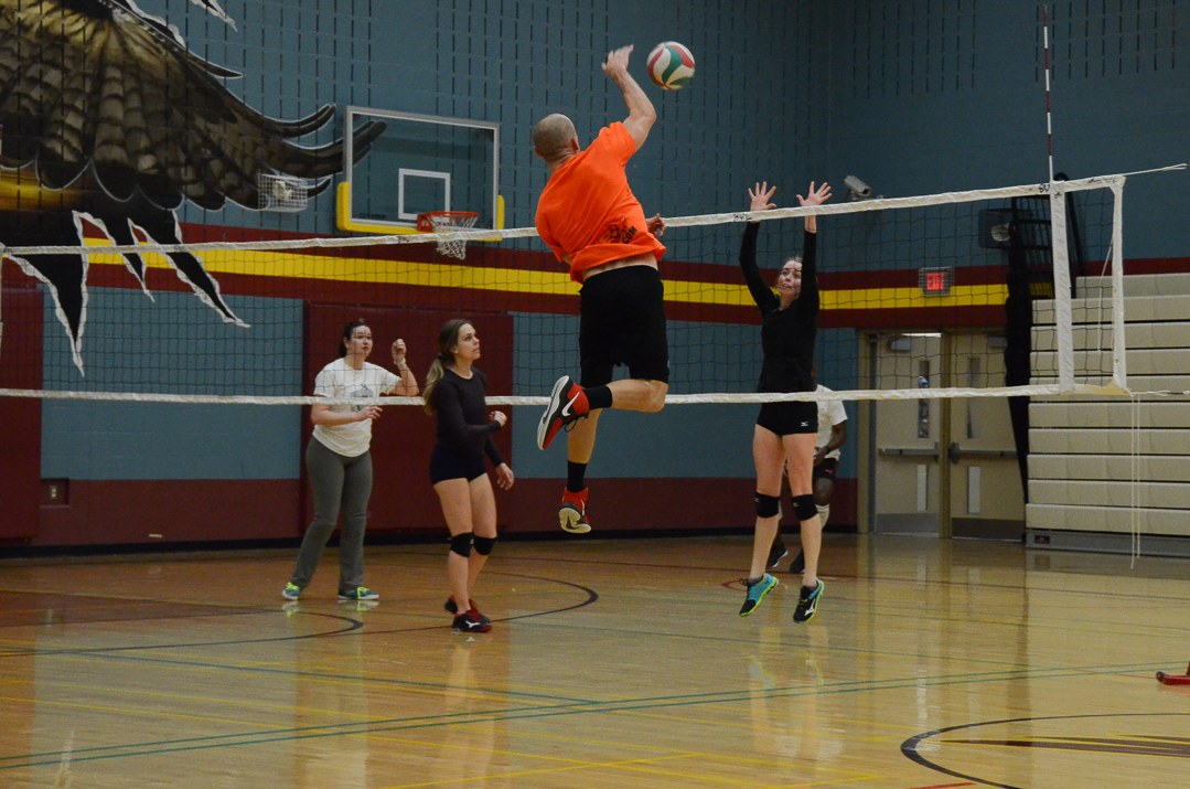 A player jumps to hit the ball over an indoor volleyball net.